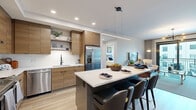 Located on Peachtree Street in Atlanta's vibrant Midtown neighborhood, this 2-bedroom, 2-bathroom residence offers a thoughtfully designed open-concept layout with modern finishes throughout. The kitchen is a standout feature, showcasing warm wood cabinetry, white quartz countertops, stainless steel appliances, a white subway tile backsplash, and a large central island with seating for multiple guests — ideal for casual dining or entertaining. A stacked in-unit washer and dryer adds everyday convenience. The living room is bright and inviting, filled with natural light from floor-to-ceiling sliding glass doors that open onto a private balcony overlooking the surrounding cityscape. The primary bedroom is generously sized, featuring a ceiling fan, sliding glass door access, and a direct connection to a spa-inspired en-suite bathroom. The primary bath is appointed with a double-sink wood vanity, illuminated mirrors, large-format tile flooring, and a glass-enclosed shower. The second bedroom offers its own en-suite bathroom and ample closet space. Both bedrooms benefit from dedicated walk-in closets with built-in shelving. Light wood-tone flooring flows throughout the main living areas, tying together this sleek, contemporary residence.