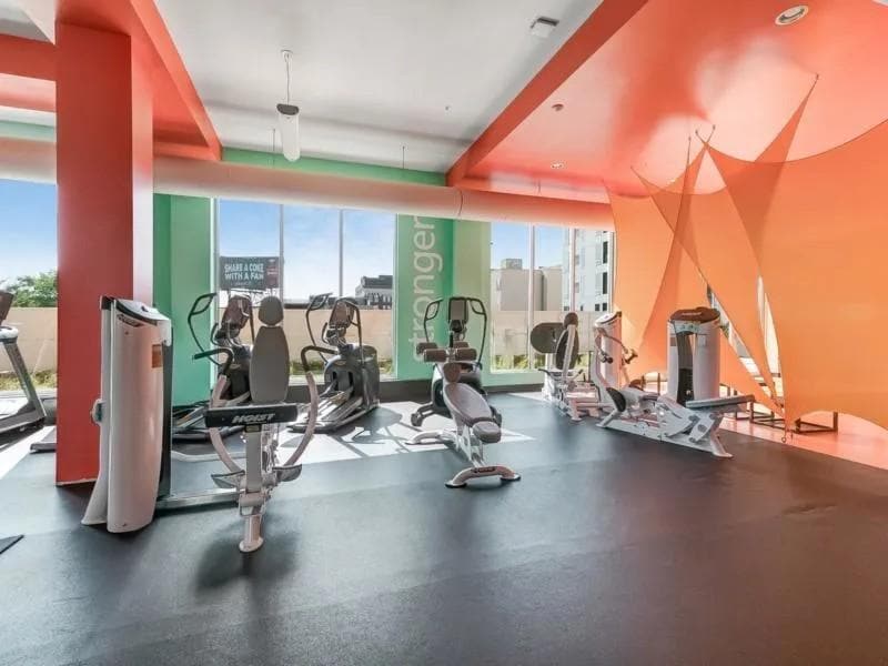 Gym with cardio machines, weight machines, and large windows.