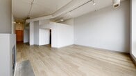 Located at 220 E Downer Pl in Aurora, IL, this one-bedroom, one-bathroom unit offers a thoughtfully designed single-floor layout with a clean, modern aesthetic. The open living area is a standout, featuring light hardwood flooring, exposed ductwork with industrial-style track lighting, and a striking floor-to-ceiling modern fireplace with a dark surround that serves as a bold focal point. Large windows allow natural light to fill the space, enhancing its bright, airy feel.

The kitchen is outfitted with contemporary flat-front cabinetry in a warm wood tone, white countertops, and a full suite of stainless steel appliances including an electric range, over-the-range microwave, and dishwasher — all set atop wood-look tile flooring.

The bedroom offers comfortable carpet flooring, white walls, built-in closet storage, and exposed ceiling details that echo the industrial character found throughout the unit. The bathroom features a tub-shower combination with white tile surround, wood-grain tile flooring, a single-sink vanity with warm wood cabinetry, white countertop, and a large mirror. Two hallways connect the rooms, providing a functional flow throughout this well-appointed urban residence.