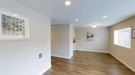 Located at 3131 Caught in San Diego, this single-floor unit presents a clean, modern aesthetic throughout its thoughtfully designed layout. The open living area is defined by warm wood-look flooring that extends seamlessly throughout the space, complemented by neutral gray walls and crisp white baseboards that create a bright, cohesive atmosphere. Recessed lighting is installed across the ceiling, providing consistent, even illumination throughout the main living area, while a side window allows natural light to filter in.

The kitchen is efficiently arranged in a galley-style configuration, maximizing functionality within its footprint. White shaker-style cabinetry lines both the upper and lower walls, offering generous storage space. Speckled granite-tone countertops provide ample workspace, and a stainless steel sink is centrally positioned along one wall. The kitchen is equipped with stainless steel appliances, including a refrigerator, a built-in microwave, and a range with a glass cooktop. Recessed lighting overhead keeps the kitchen well-lit. A partial wall separates the kitchen from the living area, maintaining a sense of openness while defining each functional zone. The overall design is clean, practical, and move-in ready.