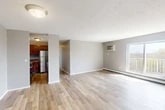 Located at 121 Lafayette Rd in Syracuse, NY, this single-floor residence offers three bedrooms, two bathrooms, and a thoughtfully arranged layout. The open living area is a standout feature, finished with light hardwood flooring that extends throughout the main living space, a textured ceiling, and a wall-mounted air conditioning unit. A sliding glass door fills the room with natural light and opens to a private balcony overlooking the surrounding landscape. Baseboard heating runs along the exterior walls, ensuring year-round comfort. The kitchen is adjacent to the living area and is equipped with warm wood cabinetry, granite-style countertops, and stainless steel appliances. The three bedrooms are carpeted in neutral tones, each with windows that allow natural light and views outside. The two bathrooms are finished consistently, featuring wood vanities with granite-topped sinks, framed mirrors with lighted fixtures, and white tile wainscoting. A dedicated entrance and closet add functional convenience to the home. The neutral gray color palette throughout creates a clean, cohesive aesthetic well-suited for everyday living.