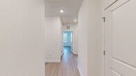 This single-floor residence is designed with a clean, contemporary aesthetic throughout. Light wood-tone flooring flows consistently across all rooms, creating a cohesive and airy atmosphere. Crisp white walls and recessed lighting illuminate the interior hallway, which connects the various living spaces with a sense of openness and ease of movement.

The kitchen stands out as a well-appointed feature space, pairing two-tone cabinetry — white upper cabinets contrasting with dark wood lower cabinets — with light granite countertops and a white subway tile backsplash. Stainless steel appliances, including a French door refrigerator, electric range, and over-the-range microwave, complete the modern finish.

Bedrooms are bright and generously proportioned, each featuring large windows fitted with horizontal blinds that frame outdoor views of palm trees and landscaping, allowing for abundant natural light. Ceiling fans add both comfort and functionality to the rooms.

Storage is well addressed throughout, with multiple walk-in closets fitted with wire shelving systems offering organized, multi-tiered storage capacity. A dedicated dining area is highlighted by a pendant light fixture and dual windows overlooking the greenery outside, contributing to the space's welcoming and light-filled character.