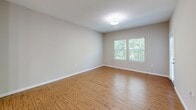 This well-appointed one-bedroom, one-bathroom residence in Durham, NC offers a thoughtfully designed single-floor layout with a comfortable, functional flow throughout. The open-concept living, dining, and kitchen area serves as the heart of the home, featuring warm hardwood-style flooring, neutral walls, and an abundance of natural light from multiple windows. The kitchen stands out with a large granite-topped island with an undermount sink, sleek white cabinetry, a subway tile backsplash, stainless steel appliances including a refrigerator, range, microwave, and dishwasher, and modern pendant lighting overhead. A door off the living area provides direct access to a private balcony. The bedroom is carpeted for comfort, includes a ceiling fan, and connects conveniently to the full bathroom, which features a granite vanity, white cabinetry, and hardwood-style flooring. Three closets offer generous storage throughout the unit. A dedicated laundry area with in-unit washer and dryer hookups, a utility room, and a welcoming entrance with louvered closet doors round out the space. Clean finishes and a neutral palette create a cohesive, move-in-ready environment.
