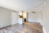 Located at 9600 E Girard Ave in Denver, CO, this single-floor, 2-bedroom, 2-bathroom unit offers a practical and comfortable layout. The open living area is finished with durable wood-style flooring, neutral gray walls, and a textured ceiling, while a ceiling fan adds functionality to the space. A sliding glass door floods the living room with natural light and provides direct outdoor access. The galley-style kitchen is efficiently designed with white cabinetry, subway tile backsplash, granite-look countertops, a breakfast bar peninsula, and black appliances including a gas range and refrigerator. Light wood-style flooring continues throughout the kitchen, lending a cohesive feel. A hallway connects the living areas to the two bedrooms, both of which feature plush carpeting, textured ceilings, and ample closet space. The primary bedroom includes a window for natural light. Both bathrooms are clean and functional, each offering a full tub-shower combo with white tile surround and chrome fixtures. Additional storage is provided through four closets and a dedicated utility room, maximizing the efficiency of the overall floor plan.