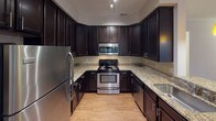 Located at 10930 Dixie Hills Dr in Charlotte, NC, this single-floor residence offers a well-designed layout with a cohesive blend of practical finishes and comfortable living spaces throughout.

The kitchen is a standout feature, showcasing rich dark cabinetry that extends to the ceiling, granite countertops, a tile backsplash, and a full suite of stainless steel appliances including a refrigerator, range, and built-in microwave. A breakfast bar with pendant lighting connects the kitchen to the adjacent living and dining areas.

The main living area features warm hardwood-style flooring, crown molding, and a large triple-panel window that fills the room with natural light and offers views of the surrounding greenery. A ceiling fan adds comfort to the open dining space nearby, which also benefits from natural light through a sizable window.

The bedrooms are carpeted and offer a quiet retreat. One bedroom includes a spacious walk-in closet with built-in shelving, while another features a standard double-door closet. Ceiling fans are present in the bedrooms for added comfort.

Both bathrooms are finished with hardwood-style flooring, dark vanity cabinetry, white countertops, and tiled tub/shower combinations with chrome fixtures, providing a clean and consistent aesthetic throughout the home.
