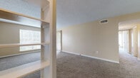 Located at 603 Hampton Cir in Jackson, MS, this single-floor, two-bedroom, two-bathroom residence offers a practical and well-organized layout. The living room serves as the central gathering space, featuring plush carpeting, neutral beige walls, a textured ceiling, and a sliding glass door fitted with vertical blinds that opens to a private balcony with outdoor views. A built-in shelving unit provides convenient storage and display space adjacent to the living area.

The primary bedroom is generously sized, equipped with a ceiling fan, a sliding glass door to the balcony, and a walk-in closet with shelving. The second bedroom also features carpeted flooring, a standard closet, and a window that allows natural light. Both rooms maintain the same warm, neutral color palette found throughout the unit.

The galley-style kitchen includes wood-toned cabinetry, a countertop peninsula, light wood-look flooring, and white appliances including a range and refrigerator. Both bathrooms are fitted with full tub-shower combinations surrounded by white square tile. A hallway connects the rooms, completing the efficient, single-level floor plan.