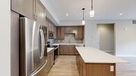 Located in the heart of Bozeman, MT, this well-designed 3-bedroom, 2-bathroom residence on West Lamme Street offers a thoughtful single-floor layout with modern finishes throughout. The open-concept kitchen and living area serves as the central hub of the home, showcasing warm-toned shaker cabinetry, a grey subway tile backsplash, white quartz countertops, and a full suite of stainless steel appliances. A center island with pendant lighting provides additional prep space and a natural gathering point. Light hardwood flooring flows throughout the main living areas, complementing the neutral, contemporary color palette. The bedrooms are carpeted for comfort, with the primary bedroom offering a generous footprint and access to a dedicated closet. A second well-sized bedroom features dual windows that frame views of the surrounding Bozeman streetscape, filling the room with natural light. The bathrooms are finished with matching cabinetry, quartz vanities, and large mirrors with overhead lighting. A dedicated laundry area houses a stacked washer and dryer unit behind a sliding panel door, maintaining a clean and organized layout. Recessed lighting and clean white ceilings complete the polished, move-in-ready aesthetic of this Bozeman residence.