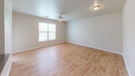 This single-story residence offers a functional and well-organized layout across several distinct living areas. The open living space features light wood-style flooring and neutral wall tones, with a ceiling fan providing overhead lighting and a window allowing natural light to filter in. A pass-through counter connects the living area to the kitchen, which is equipped with warm wood cabinetry, dark granite-style countertops, and black appliances including a range, microwave, and refrigerator.

The bedrooms feature plush carpeting and neutral walls. One bedroom includes a ceiling fan, dual windows for added natural light, and generous proportions, while another benefits from a distinctive arched window that adds architectural character. Additional bedroom space offers a quieter, more enclosed feel with easy access to adjoining areas.

Two full bathrooms serve the residence. Both include a tub and shower combination with white tile surrounds and wood-style flooring. One bathroom is notably equipped with multiple grab bars for accessibility, along with a vanity sink. The other bathroom features white cabinetry above the toilet and a countertop vanity. Throughout the home, clean white trim and consistent finishes contribute to a cohesive, low-maintenance aesthetic.