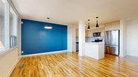 Located at 25 Woodridge Cres in Ottawa's K2B neighbourhood, this one-bedroom, one-bathroom unit offers a thoughtfully designed layout across a single floor. The open-concept living and kitchen area forms the heart of the space, unified by warm, light-toned hardwood-style flooring that runs throughout. A striking cobalt blue accent wall adds a bold pop of colour to the living area, complemented by sleek pendant lighting that lends a modern, curated feel.

The kitchen is well-appointed with light wood cabinetry, a white quartz peninsula island, and a full suite of stainless steel appliances including a French door refrigerator, electric range, and over-the-range microwave. Large windows along the living area flood the space with natural light and offer open views of the surrounding Ottawa skyline.

The bedroom is a calm and comfortable retreat, featuring soft sage-toned walls, ample built-in wardrobe storage, and natural light from a window with outdoor views. The bathroom is clean and modern, finished with large-format white tiles surrounding a full soaker bathtub. In-unit laundry adds further convenience. Overall, the space presents a bright, contemporary, and efficiently organized home.