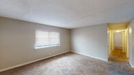 Located at 235 James I Harrison Jr Pkwy E in Tuscaloosa, Alabama, this single-floor unit presents a clean, functional layout designed for comfortable everyday living. Throughout the space, neutral beige walls and wall-to-wall carpeting create a cohesive, understated aesthetic, while textured popcorn ceilings are consistent across the rooms.

The living area is generously proportioned, featuring a pass-through window that connects directly to the kitchen — a practical design detail that enhances the sense of openness between spaces. Natural light filters in through horizontal blinds in several rooms, contributing to a bright and airy atmosphere.

The bedrooms are well-sized, each with soft carpeted flooring and windows with blinds. At least one bedroom includes a built-in closet with bifold doors, offering convenient storage. The neutral color palette throughout lends itself to easy personalization.

The bathrooms are clean and functional. One features a white vanity with cabinet storage, a wall-mounted medicine cabinet mirror, and wood-look flooring. The second includes a full tub-and-shower combination with white tile surround and tile flooring, providing a practical bathing option.

Overall, the space maintains a straightforward, move-in-ready character with consistent finishes throughout its single floor.