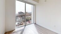 Located at 49 Walnut St S in Hamilton, Ontario, this two-bedroom, two-bathroom unit offers a thoughtfully designed layout across a single floor. Light wood-tone flooring flows throughout the space, complementing the clean, modern aesthetic defined by crisp white walls and contemporary finishes.

Both bedrooms feature expansive floor-to-ceiling windows that frame views of the surrounding Hamilton cityscape, filling the rooms with natural light and creating an airy, open feel. The primary bedroom is a cozy, well-proportioned retreat.

The two bathrooms are finished to a consistent modern standard. One features a glass-enclosed shower, a floating wood-toned vanity with a white quartz countertop, an oval mirror, and light wood-look tile flooring. The second bathroom doubles as a functional laundry space, housing a stacked washer and dryer unit alongside a matching wood-toned vanity with a white countertop and framed mirror.

The kitchen, visible in the overall layout, is equipped with full-sized stainless steel appliances including a refrigerator and oven, cabinetry, and a central island. A hallway connects the living spaces efficiently. Throughout the unit, the consistent use of neutral tones, modern hardware, and quality materials creates a clean, cohesive, and inviting atmosphere.
