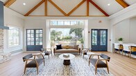 Located at 1520 N Beckley Ave in Dallas, TX, this single-floor space offers a thoughtfully designed interior that blends modern elegance with warm, rustic character. The living room is an architectural showpiece, boasting soaring vaulted ceilings with exposed wood beam trusses and light hardwood flooring throughout. A striking stone fireplace with a slate-blue surround serves as the focal point of the living area, complemented by large French doors and expansive floor-to-ceiling glass panels that flood the space with natural light and offer views of an outdoor pool area. The kitchen is equally impressive, featuring navy-blue cabinetry with brass hardware, a crisp white countertop, and a vibrant teal subway tile backsplash. A floor-to-ceiling slatted wood accent wall adds warmth and texture, while pendant lighting illuminates a generous white island with bar seating. Stainless steel appliances, including a full-size French door refrigerator, complete the functional layout. A connecting hallway provides access between areas, maintaining the open and airy flow of the space. Interior French doors with grid-pane glazing add a refined architectural detail, further enhancing the bright, welcoming ambiance throughout this well-appointed Dallas property.