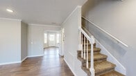This two-story home is thoughtfully laid out across two floors, with the main living areas on the ground floor and bedrooms above. The main level features a welcoming entryway with a carpeted staircase framed by a classic white balustrade, crown molding, and textured ceilings that carry throughout the home. The living room is generously proportioned, finished with warm hardwood-style flooring, recessed lighting, and neutral gray walls that create a clean, cohesive atmosphere. The kitchen stands out with white shaker-style cabinetry, granite countertops, a subway tile backsplash, stainless steel appliances, and a deep undermount sink — offering both style and functionality. A utility room and hallway complete the ground floor.

Upstairs, the two bedrooms are carpeted for comfort and feature windows that bring in natural light and outdoor views. The primary bedroom offers a notably spacious footprint. Three bathrooms are distributed across the home, each finished with granite-topped white vanities, hardwood-style flooring, and tub-shower combinations with brushed nickel fixtures. Two closets provide practical storage throughout the upper level.