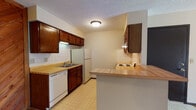 Located at 2759 North Amidon Street in Wichita, Kansas, this single-floor unit offers a practical and functional layout designed for comfortable everyday living. The kitchen is a standout feature, outfitted with rich dark wood cabinetry, light butcher block-style countertops, white tile backsplash, and white appliances including a dishwasher and full-size refrigerator. A peninsula counter with bar-height overhang provides an informal dining or workspace option, and the kitchen is finished with easy-care tile flooring. A distinctive diagonal wood-paneled accent wall adds a warm, rustic character to the kitchen area. The living room is generously sized, featuring neutral carpet and a sliding glass door dressed with vertical blinds that allows natural light to fill the space. The bedroom is comfortably appointed with carpet, a ceiling fan with light fixture, a window for additional natural light, and a sliding closet with ample storage. The full bathroom includes a tub-shower combination, a dark wood vanity with storage, tile flooring, and clean white fixtures. Throughout the unit, textured ceilings and neutral tones create a cohesive, understated aesthetic well-suited for a range of personal styles.