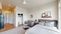 This well-appointed studio in Salem, Oregon offers a smart, efficient layout across a single floor, making excellent use of every square foot. The main living area seamlessly combines sleeping, lounging, and living functions, featuring warm-toned hardwood flooring, crisp white walls, and soaring ceilings that lend an open, airy feel. A ceiling fan adds both comfort and style overhead. A spacious reach-in closet provides ample storage, while a dedicated wall shelf offers additional display space. Large floor-to-ceiling windows flood the room with natural light, and a private balcony door opens to sweeping outdoor views of the surrounding Salem landscape — a standout feature of the space.

The kitchen is thoughtfully designed with rich walnut-toned cabinetry, quartz countertops, a neutral tile backsplash, and matte black fixtures. Full appliances including an electric range, built-in microwave, and dishwasher make this kitchen as functional as it is attractive. In-unit stacked laundry is also conveniently included.

The bathroom features a clean, modern aesthetic with a warm wood vanity, white countertop, matte black faucet, and framed wall art, maintaining a consistent design language throughout. The overall ambiance is contemporary and welcoming, blending modern finishes with a warm, livable atmosphere.