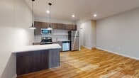 Located at 1011 S Saddle Creek Rd in Omaha, Nebraska, this thoughtfully designed single-floor unit offers a clean, contemporary aesthetic throughout. The kitchen is a standout feature, outfitted with rich dark-toned cabinetry, a full suite of stainless steel appliances including a refrigerator, electric range, built-in microwave, and dishwasher, all set against a classic white tile backsplash. Light-toned granite countertops and a kitchen island with a marble-style top provide ample prep and dining space. Warm hardwood-style flooring runs throughout the main living and kitchen areas, adding a welcoming character to the space. The bedroom is finished with soft carpeting and features a large floor-to-ceiling window that floods the room with natural light and offers views of the surrounding neighborhood. The bathroom is well-appointed with a full tub-shower combination, dark wood vanity cabinetry, a granite-topped countertop, an integrated sink, and open shelving for convenient storage. Neutral gray walls and recessed lighting throughout contribute to a bright, modern ambiance that makes the entire unit feel open and move-in ready.