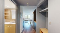 Located at 275 Research Pkwy in Meriden, CT, this thoughtfully designed one-bedroom, one-bathroom unit makes efficient use of its compact footprint across a single floor. Wood-look flooring runs throughout, providing a warm and cohesive aesthetic that ties each room together.

The kitchen is outfitted with contemporary gray cabinetry, a light wood countertop, a built-in oven, an induction cooktop, a stainless steel sink, and an overhead range hood. Open wood shelving above the counter adds additional storage and a modern, functional touch.

The living area is bright and inviting, benefiting from large windows that frame views of the surrounding greenery and neighborhood. The space accommodates a seating and dining arrangement comfortably.

The bedroom is a well-proportioned private retreat featuring large windows on two walls, filling the room with natural light and offering pleasant outdoor views of trees and the surrounding area. A wall-unit HVAC system ensures year-round comfort.

A dedicated closet with built-in shelving and a hanging rod provides organized storage. The bathroom is clean and straightforward, finished with wood-toned cabinetry and wood-look flooring. A hallway connects the rooms efficiently, completing this well-organized and modern living space.