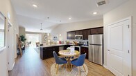 This single-floor residence offers a thoughtfully designed open-concept layout that seamlessly connects the kitchen, dining, and living areas. The kitchen is outfitted with rich dark cabinetry, granite countertops, stainless steel appliances including a refrigerator, range, and microwave, and a peninsula that provides additional workspace and a natural transition to the dining area. Light wood-tone flooring runs throughout the main living spaces, adding warmth and continuity.

The living room features vaulted ceilings that lend an airy, expansive feel, complemented by recessed lighting and a ceiling fan. A flex room with sliding glass doors opens to an outdoor view of a scenic waterfront, filling the space with natural light and offering a versatile area ideal for a home office or fitness space.

The bedrooms are carpeted and comfortably sized, each with ceiling fans and windows that invite natural light. The primary bedroom includes a generous walk-in closet outfitted with wire shelving and hanging rods, providing ample storage. A full bathroom features wood-look flooring, a tub-shower combination, a dark-cabineted vanity with granite countertops, and recessed lighting. The overall palette throughout is neutral and cohesive, creating a calm, modern ambiance.