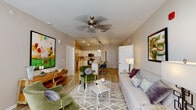 Located in Clarksville, Indiana, this single-floor residence offers a thoughtfully designed layout that balances comfort and modern style. The open-concept living area is bright and welcoming, featuring wood-look flooring, a ceiling fan, and large windows that draw in generous natural light. The space flows seamlessly into the kitchen, which is outfitted with crisp white shaker cabinets, light granite countertops, a kitchen island with bar seating, and a full suite of stainless steel appliances including a refrigerator, dishwasher, range, and over-the-range microwave. A pantry provides additional storage convenience. The two bedrooms are carpeted for comfort and each feature ceiling fans and ample natural light from multiple windows. Both bathrooms are well-appointed with rich dark wood vanities, dual sinks, white countertops, and wood-look tile flooring. One bathroom is positioned as an en-suite, connecting directly to a bedroom for added privacy. The neutral color palette of warm beige and white tones throughout the home creates a clean, cohesive ambiance that is both modern and inviting, making this Clarksville residence a functional and attractive living space.