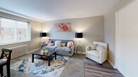 Located at 1553 Parkline Dr in Pittsburgh, PA, this one-bedroom, one-bathroom unit offers a practical and comfortable layout across a single floor. The living room serves as the welcoming centerpiece of the space, featuring neutral gray walls, plush carpeting, and hardwood-style flooring near the entryway. A large window floods the room with natural light, while a pass-through counter connects to an adjacent area, adding an open, airy feel. The dining area is situated nearby and comfortably accommodates a four-seat dining table, complemented by a ceiling fan with lighting and a wall-mounted television, making it both functional and versatile. The bedroom is a quiet, well-proportioned retreat with a window providing natural light and a classic radiator for heating. Soft carpeting and clean, neutral tones create a calm atmosphere throughout. The bathroom is straightforward and functional, featuring a full-size tub and shower combination with a small window for ventilation. Throughout the unit, the consistent use of soft gray and warm neutral tones creates a cohesive, understated aesthetic. This space is well-suited for those seeking an efficient and comfortable home in the Pittsburgh area.