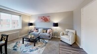 Located at 1553 Parkline Dr in Pittsburgh, PA, this one-bedroom, one-bathroom unit offers a practical and comfortable layout across a single floor. The living room serves as the welcoming centerpiece of the space, featuring neutral gray walls, plush carpeting, and hardwood-style flooring near the entryway. A large window floods the room with natural light, while a pass-through counter connects to an adjacent area, adding an open, airy feel. The dining area is situated nearby and comfortably accommodates a four-seat dining table, complemented by a ceiling fan with lighting and a wall-mounted television, making it both functional and versatile. The bedroom is a quiet, well-proportioned retreat with a window providing natural light and a classic radiator for heating. Soft carpeting and clean, neutral tones create a calm atmosphere throughout. The bathroom is straightforward and functional, featuring a full-size tub and shower combination with a small window for ventilation. Throughout the unit, the consistent use of soft gray and warm neutral tones creates a cohesive, understated aesthetic. This space is well-suited for those seeking an efficient and comfortable home in the Pittsburgh area.