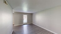Located at 1225 Boone Hill Rd in Summerville, SC, this single-story, 3-bedroom, 2-bathroom home offers a practical and well-organized layout. Consistent wood-look vinyl flooring and soft neutral gray walls flow throughout, creating a cohesive and clean aesthetic from room to room.

The living room is a generous open area bathed in natural light from a glass-paneled exterior door, providing a welcoming entry point into the home. The galley-style kitchen is efficiently designed with white cabinetry, light countertops, a double-basin sink, and black appliances including a full-size refrigerator and dishwasher. A window at the end of the kitchen draws in additional natural light.

All three bedrooms feature the same wood-look flooring and neutral tones, with windows that offer outdoor views and allow natural light to fill each room. The spacious primary bedroom provides ample room for furnishings. The secondary bedrooms are well-proportioned and include closet access.

The two bathrooms are clean and functional. One features an extended vanity with a single sink, bright mirror lighting, and access to a separate water closet, while the other includes a full tub-shower combo unit. Textured ceilings are present throughout, adding a classic residential character to the home.