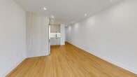This thoughtfully designed studio unit at 2213 offers a clean, modern aesthetic with high-quality finishes across its single floor. The open-concept living area is bright and airy, featuring warm honey-toned hardwood flooring and crisp white walls that amplify the natural light streaming in through large windows offering urban city views. Recessed lighting throughout enhances the well-lit ambiance.

The kitchen is a standout feature, designed with light wood cabinetry accented by matte black hardware, complemented by a striking marble-effect quartz backsplash and countertops. Stainless steel appliances — including a range, over-the-range microwave, and dishwasher — along with a built-in refrigerator, provide full functionality in a compact, efficient layout.

The bathroom maintains the same contemporary design language, showcasing a light wood vanity topped with a veined marble-effect quartz countertop, matte black fixtures and accessories, neutral tile flooring, and a glass-enclosed shower. The cohesive design palette of soft neutrals, natural wood tones, and black accents gives this unit a polished, move-in ready appeal suited for modern urban living.