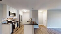 Located at 795 Saint Charles Dr in Thousand Oaks, CA, this single-floor residence offers a thoughtfully updated interior with a clean, modern aesthetic throughout. The kitchen is a standout feature, showcasing white shaker cabinetry, dark countertops, a classic subway tile backsplash, and a full suite of stainless steel appliances including a gas range, over-the-range microwave, and refrigerator. A peninsula with an integrated sink provides additional prep space and creates a natural transition into the open living area, which is finished with warm wood-look flooring and a ceiling fan. Sliding glass doors in the living space open to a private patio, allowing natural light to fill the room and offering pleasant outdoor views. The primary bathroom features an extended white vanity with dark countertops, a wide mirror, and Hollywood-style lighting, with a combined tub and shower tucked nearby. A second bathroom mirrors the refined finishes with white cabinetry and dark countertops. A dedicated in-unit laundry nook houses a full-size stacked washer and dryer, adding everyday convenience. Consistent wood-look flooring, neutral wall tones, and modern light fixtures unify the space with a fresh, cohesive style.