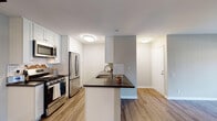 Located at 795 Saint Charles Dr in Thousand Oaks, CA, this single-floor residence offers a thoughtfully updated interior with a clean, modern aesthetic throughout. The kitchen is a standout feature, showcasing white shaker cabinetry, dark countertops, a classic subway tile backsplash, and a full suite of stainless steel appliances including a gas range, over-the-range microwave, and refrigerator. A peninsula with an integrated sink provides additional prep space and creates a natural transition into the open living area, which is finished with warm wood-look flooring and a ceiling fan. Sliding glass doors in the living space open to a private patio, allowing natural light to fill the room and offering pleasant outdoor views. The primary bathroom features an extended white vanity with dark countertops, a wide mirror, and Hollywood-style lighting, with a combined tub and shower tucked nearby. A second bathroom mirrors the refined finishes with white cabinetry and dark countertops. A dedicated in-unit laundry nook houses a full-size stacked washer and dryer, adding everyday convenience. Consistent wood-look flooring, neutral wall tones, and modern light fixtures unify the space with a fresh, cohesive style.