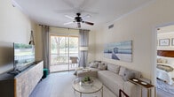 This thoughtfully designed two-bedroom, two-bathroom residence in Fort Myers, Florida offers a comfortable and functional single-story layout. The open-concept kitchen is a standout feature, showcasing white cabinetry, stainless steel appliances, and a generous countertop peninsula — ideal for both meal preparation and casual dining. Wood-look flooring flows throughout the main living areas, complementing the warm, neutral color palette.

The living room is bright and inviting, with a ceiling fan overhead, crown molding, and sliding glass door access to a private balcony that overlooks lush greenery. The primary bedroom features a tray ceiling, ceiling fan, large windows with outdoor views, and its own sliding door to the balcony. The en suite bathroom offers a dual-sink vanity, a walk-in shower, and tile flooring. The second bedroom includes a closet with sliding doors and its own ceiling fan with tray ceiling detail. The second bathroom provides a full tub-shower combination with clean white tile finishes.

Additional highlights include two closets for ample storage, a dedicated laundry room with a full-size washer and dryer, and a connecting hallway that ties the layout together efficiently. Located at 9000 Colby Dr in Fort Myers, FL, this residence combines practical amenities with a relaxed Florida aesthetic.