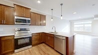 Located at 3800 Jeffers Pkwy NW in Prior Lake, MN, this thoughtfully designed one-bedroom, one-bathroom residence offers a comfortable and efficient layout across a single floor. The open-concept kitchen and living area serves as the heart of the space, featuring warm-toned cabinetry, light quartz countertops, and a full suite of stainless steel appliances including a range, microwave, dishwasher, and refrigerator. A peninsula with pendant lighting above provides both additional prep space and a natural visual divide between the kitchen and living area. Light hardwood-style flooring runs throughout the main living spaces, enhancing the bright, airy atmosphere. Large windows in the living area frame scenic views of the surrounding landscape and flood the space with natural light. The bedroom is a comfortable size, finished with plush carpet and its own generous window offering continued outdoor views, along with access to a dedicated closet. Crown molding adds a polished detail throughout the main areas. The full bathroom is clean and functional, featuring a tub-shower combination, wood-toned vanity with a white countertop, and matching hardwood-style flooring that ties the space together cohesively.