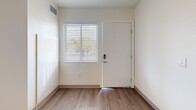 Located at 601 Orange Ave NE in Roanoke, Virginia, this single-floor unit offers a clean, modern aesthetic throughout its well-organized layout. The interior design emphasizes bright, neutral tones with white walls and crisp trim that create a fresh, open atmosphere across all rooms.

The main living area features smooth wood-style flooring that extends toward the entry, where a keypad-secured front door is flanked by a window fitted with horizontal blinds, allowing natural light to filter in. The galley-style kitchen is thoughtfully appointed with white shaker cabinetry, light stone-pattern countertops, stainless steel appliances including a dishwasher and refrigerator, and a stainless undermount sink — all set atop light wood-tone flooring.

Sleeping areas are finished with plush carpeting for added comfort, providing a softer contrast to the hard-surface floors elsewhere. Each carpeted room includes windows that bring in natural light. A dedicated laundry closet houses a stacked washer and dryer unit, conveniently positioned adjacent to the bathroom.

The bathroom features wood-style flooring, a white vanity with storage cabinetry, a large mirror, and a tub-shower combination, maintaining the unit's consistent clean, white aesthetic throughout.