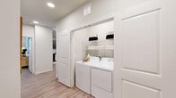 Located at 5901 County Road 277 in Melissa, Texas, this single-story, 2-bedroom, 3-bathroom residence offers a clean, modern aesthetic with consistent light wood-tone flooring and a crisp white palette throughout. The open-concept living room welcomes natural light through large windows, complemented by a ceiling fan and ample wall space for décor. It flows naturally toward the kitchen, which features rich dark wood cabinetry, stainless steel appliances, granite countertops, and a peninsula island ideal for casual dining or meal prep. The primary bedroom is a comfortable retreat with natural light from dual windows, a ceiling fan, and direct access to its own bathroom. That bathroom offers a granite-topped vanity with dark wood cabinetry and a full soaking tub. Two additional bathrooms serve the home, one featuring large-format marble-style tile surrounding the tub-shower combination. Both bedrooms include closets, with wire shelving systems maximizing storage capacity. A dedicated laundry closet with side-by-side washer and dryer hookups and overhead shelving adds everyday convenience. The hallway connects all spaces efficiently, maintaining a logical and functional flow throughout the home. Light wood flooring, recessed lighting, and neutral tones create a cohesive, inviting ambiance across every room.