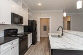 Located on Seabiscuit Lane in Greensboro, NC, this single-story residence presents a thoughtfully designed layout with a cohesive, contemporary aesthetic. The interior is unified by a neutral color palette of soft whites and warm greiges, with light wood-look flooring running through the main living and kitchen areas, while plush carpet adds comfort to the bedrooms.

The kitchen serves as a central hub of the home, anchored by a substantial island with a marble-style countertop and pendant lighting overhead. White shaker-style cabinetry extends to the ceiling, complemented by a subway tile backsplash and black appliances, including a range, microwave, and refrigerator. A dedicated walk-in pantry provides generous storage. Recessed lighting illuminates the space throughout.

The bedrooms feature ceiling fans, ample natural light from windows with blinds, and neutral carpet. Multiple bathrooms are outfitted with white cabinetry, dark granite countertops, and wood-look tile flooring. One bathroom includes a tub-shower combo, while another offers a single-vanity layout. A dedicated laundry space with wire shelving, washer/dryer connections, and a utility hookout panel adds functional convenience. The overall ambiance is clean, bright, and move-in ready.