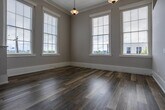 Located at 101 E Fifth Ave in Knoxville, Tennessee, this single-floor unit showcases a thoughtful blend of historic character and contemporary updates. The open living area immediately impresses with soaring ceilings, exposed structural details, and large double-hung windows that flood the space with natural light and offer views of the surrounding Knoxville streetscape. Pendant lighting adds a classic touch overhead, while durable wood-look flooring runs throughout the main areas, enhancing warmth and continuity.

The kitchen is well-appointed with medium-toned cabinetry, stainless steel appliances including a refrigerator, range, microwave, and dishwasher, and a layout that opens toward the bright, windowed living space. A dedicated hallway connects the main living area to private rooms, featuring soaring ceilings with a skylight above, adding an airy quality to the passage.

The bedroom offers carpeted flooring, impressively tall ceilings with exposed architectural elements, and a built-in closet with shelving behind classic paneled doors. The bathroom is designed with accessibility in mind, including a walk-in shower unit equipped with grab bars and a built-in seat, alongside wood-look flooring. A stacked Whirlpool washer and dryer unit provides in-unit laundry convenience, tucked neatly behind a warm wood-framed door.