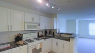 Located at 150 Southfield Ave in Stamford, Connecticut, this single-floor residence offers a thoughtfully designed living space with a functional and inviting layout. The kitchen is a standout feature, showcasing crisp white cabinetry that extends to the ceiling, providing generous storage throughout. Dark countertops offer a striking contrast against the white cabinets, creating a clean and classic aesthetic. The kitchen is equipped with a gas range, over-the-range microwave, and a double basin sink, making it well-suited for everyday cooking and entertaining. Track lighting overhead ensures bright, even illumination across the workspace. A pass-through counter connects the kitchen to the adjacent living area, promoting an open, airy feel that enhances the flow between spaces. The light-toned flooring carries throughout, contributing to a cohesive and welcoming atmosphere. The single-floor configuration ensures ease of movement and accessibility throughout the home. Situated in Stamford's Southfield neighborhood, the residence benefits from a well-established Connecticut location with convenient access to local amenities, transportation, and the waterfront. Overall, this home combines practical design with comfortable living in a sought-after Stamford address.