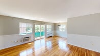 Located at 5049 Riverdale in Riverdale Park, Maryland, this two-story residence offers two bedrooms and two bathrooms across a well-organized layout spanning two floors. The main level houses the combined living and dining area, kitchen, and a bathroom, while the upper level contains the bedrooms and second bathroom.

The living and dining area is an open, light-filled space defined by warm hardwood floors that extend throughout the home. Multiple windows allow generous natural light and outdoor views of surrounding greenery, while a sliding glass door provides additional brightness. A pendant light fixture anchors the dining area, and white wainscoting along the lower walls adds a classic architectural detail. A striking open-tread metal staircase connects the two floors, serving as a functional design element.

The kitchen features warm wood cabinetry, dark granite-style countertops, a mosaic tile backsplash, and a classic patterned tile floor. Stainless steel appliances, including a gas range and refrigerator, are complemented by an in-unit washer for added convenience.

Upstairs, both bedrooms feature the same hardwood flooring, ceiling fans, and windows with outdoor views. One bathroom includes a glass-enclosed shower/tub combination, while the second offers a clean, simply appointed vanity layout.