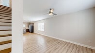 Located at 500 Dalton Way in Little River, South Carolina, this two-story home offers a clean, modern aesthetic across two equally sized floors. The main level features an open-concept living room and kitchen, unified by light-toned luxury vinyl plank flooring and a neutral color palette. The living area is outfitted with a contemporary ceiling fan and recessed lighting, with natural light flowing in through multiple windows dressed with white blinds. The kitchen is a standout feature, showcasing gray shaker-style cabinetry, granite countertops, a subway tile backsplash, stainless steel appliances including a French door refrigerator, and a central island with pendant lighting. Three well-appointed bathrooms are found throughout the home, each featuring granite-topped vanities and wood-toned flooring; one includes a full soaking tub and shower combination. The upper level hosts the bedrooms, including a generously sized primary suite with a walk-in closet, plush carpet flooring, and a ceiling fan. The secondary bedroom also offers carpet, natural light, and its own ceiling fan. With three closets distributed across the home, storage is plentiful. The consistently modern finishes and cohesive design make this home a comfortable and stylish residence.