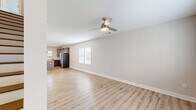 Located at 500 Dalton Way in Little River, South Carolina, this two-story home offers a clean, modern aesthetic across two equally sized floors. The main level features an open-concept living room and kitchen, unified by light-toned luxury vinyl plank flooring and a neutral color palette. The living area is outfitted with a contemporary ceiling fan and recessed lighting, with natural light flowing in through multiple windows dressed with white blinds. The kitchen is a standout feature, showcasing gray shaker-style cabinetry, granite countertops, a subway tile backsplash, stainless steel appliances including a French door refrigerator, and a central island with pendant lighting. Three well-appointed bathrooms are found throughout the home, each featuring granite-topped vanities and wood-toned flooring; one includes a full soaking tub and shower combination. The upper level hosts the bedrooms, including a generously sized primary suite with a walk-in closet, plush carpet flooring, and a ceiling fan. The secondary bedroom also offers carpet, natural light, and its own ceiling fan. With three closets distributed across the home, storage is plentiful. The consistently modern finishes and cohesive design make this home a comfortable and stylish residence.