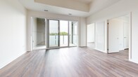 Located at 3060 Pharmacy Ave in Toronto's northeast end, this well-appointed 3-bedroom, 1-bathroom unit offers a clean, modern aesthetic across a single thoughtfully laid-out floor. Rich hardwood-style flooring runs throughout, complementing the crisp white walls and creating a warm, cohesive feel from room to room. The central hallway connects all areas efficiently, with in-suite stacked laundry conveniently tucked along its length. The kitchen is well-equipped with white gloss cabinetry, a tile backsplash, and a full suite of stainless steel appliances including a refrigerator, stove, and dishwasher. The open living area extends seamlessly to a private balcony through full-height sliding glass doors, bringing in abundant natural light and tree-lined views. Each of the three bedrooms features the same warm flooring and generous windows — the primary bedroom benefits from tall ceilings and closet space, while secondary bedrooms enjoy bright outlooks over the surrounding greenery. The bathroom is finished with floor-to-ceiling subway tile surrounding a soaker tub, a white vanity with undermount sink, and brushed chrome fixtures. The space presents a modern, move-in-ready environment suited for families or shared living.
