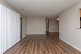 Located at 2111 Club Dr in Dalton, Georgia, this single-floor residence offers a practical and comfortable layout designed for everyday living. The open living area is finished with durable wood-look flooring and is filled with natural light through a large sliding glass door fitted with vertical blinds, providing direct access to an outdoor space. The galley-style kitchen is well-appointed with warm oak cabinetry, dark countertops, and black appliances including a refrigerator, range, and dishwasher, all set atop wood-look flooring for easy maintenance. Multiple bedrooms feature plush wall-to-wall carpeting, neutral-toned walls, and generous sliding-door closets offering ample storage. Windows fitted with horizontal blinds allow natural light to filter into each bedroom while maintaining privacy. The overall layout, as seen in the dollhouse view, flows efficiently from the living and kitchen areas through to the private bedroom spaces, with interior doors providing clear separation between common and private zones. The consistent neutral color palette and functional finishes throughout give the space a clean, move-in-ready feel suited for a variety of living arrangements.