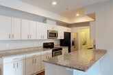 Located at 18248 W 12 Mile Rd in Southfield, Michigan, this single-floor, 2-bedroom, 2-bathroom residence offers a thoughtfully designed layout with modern finishes throughout. The open-concept kitchen, dining, and living area serves as the heart of the home, showcasing granite countertops, a large kitchen island, crisp white cabinetry, and a full suite of stainless steel appliances including a range, built-in microwave, and French door refrigerator. Durable wood-tone flooring runs through the main living areas, adding warmth and continuity to the space. Both bedrooms are carpeted and finished in neutral tones, offering a comfortable retreat. The primary bedroom is generously sized and supported by ample closet storage. The bathrooms are well-appointed, with one featuring a glass-enclosed walk-in shower clad in large-format tile with mosaic tile flooring and chrome grab bars. A dedicated in-unit laundry room provides added convenience with a stacked washer and dryer. Additional features include three closets, a welcoming entrance, and a private patio. The overall aesthetic is clean and contemporary, with recessed lighting and neutral gray walls creating a bright, move-in ready environment.