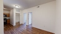 This single-floor unit accommodates four bedrooms and one bathroom within a thoughtfully organized layout. Dark wood-look flooring runs consistently throughout the entire space, providing a cohesive aesthetic that contrasts cleanly with the white walls and crisp trim visible in every room.

The kitchen features warm oak cabinetry, granite-style countertops, a double-basin sink, and black appliances including an electric range, built-in microwave, and dishwasher. Ample upper and lower cabinet storage maximizes the functionality of the compact space.

The primary bedroom is the most spacious of the four rooms, highlighted by a ceiling fan, elevated ceilings, and sliding glass doors that open onto a private balcony with outdoor views. The additional bedrooms are well-proportioned and bright, each finished with the same consistent flooring and neutral white walls.

The single bathroom is efficiently designed, offering a full tub-shower combination with tile surround, a wood-vanity with granite-style countertop, a mirror, and an adjacent closet with built-in shelving for added storage. A dedicated closet elsewhere in the unit provides further organizational flexibility. Ceiling fans in multiple rooms and consistent HVAC venting contribute to a practical and comfortable living environment throughout.