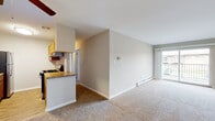 This single-floor residence in Justice, Illinois offers a well-organized layout that balances comfort and functionality throughout. The open-concept living area is finished with neutral-toned carpet and is bathed in natural light from a large sliding glass door that leads to a private balcony, providing outdoor views of the surrounding neighborhood. A wall-mounted air conditioning unit and baseboard heating ensure year-round climate control. Adjacent to the living area, the kitchen features warm wood cabinetry, granite-style countertops, a gas range, dishwasher, and refrigerator, all set on light hardwood flooring. A ceiling fan overhead adds to the kitchen's comfortable atmosphere. The bedrooms are spacious and carpeted, each with generous closet space — one room includes a sliding-door closet with built-in wire shelving — and windows that bring in natural light. Baseboard heating is present throughout the bedrooms as well. The bathroom is clean and functional, showcasing wood-look flooring, a tiled tub-shower combination, a single vanity with under-sink storage, and a large wall mirror with overhead lighting. Clean, neutral finishes throughout give this residence a move-in-ready appeal.