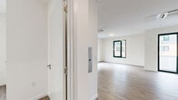 Located at 125 South Harrison Street in East Orange, NJ, this well-designed one-bedroom, one-bathroom residence offers a clean, contemporary aesthetic across a single floor. The open-concept kitchen and living area serves as the heart of the unit, featuring light wood-look flooring, crisp white walls, and abundant natural light from large dark-framed windows. The kitchen is outfitted with stainless steel appliances — including a range, over-the-range microwave, and dishwasher — complemented by two-tone cabinetry with glossy white upper cabinets, wood-toned lower cabinets, and a subway tile backsplash. A ceiling-mounted HVAC unit ensures year-round comfort in the living space, which opens directly onto a private balcony through sliding glass doors. The bedroom is a well-proportioned, quiet retreat with its own window providing natural light and neighborhood views. Two closets offer generous storage throughout the unit. The bathroom features wood-look flooring, a white vanity with mirrored medicine cabinet, and clean, minimal finishes. A dedicated utility room completes the layout. The overall design is modern and move-in ready, with a neutral palette and quality finishes throughout.