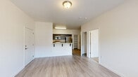 Located at 1900 Poplar St in Forest Grove, Oregon, this well-designed one-bedroom, two-bathroom unit offers a thoughtful single-level layout that maximizes every square foot of its compact footprint. The open-concept living and kitchen area serves as the heart of the home, with light-toned wood-look flooring flowing throughout the main spaces and large windows that invite natural light. A private exterior door from the living area provides convenient outdoor access.

The kitchen is a standout feature, equipped with stainless steel appliances — including a refrigerator, range, and over-the-range microwave — complemented by dark wood cabinetry and granite-style countertops. A raised breakfast bar provides casual seating and defines the kitchen's boundary with the living space. An open built-in shelving area adds functional storage nearby.

The bedroom is carpeted for warmth and comfort, features a large window with views of the surrounding neighborhood, and includes a dedicated closet with built-in shelving. Two bathrooms serve the unit, one of which includes a full soaking tub with shower and safety grab bar. The second bathroom features a granite-topped vanity and convenient access to an in-unit stacked washer and dryer. The overall aesthetic is clean, modern, and move-in ready.