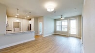 This single-story, 2-bedroom, 2-bathroom home offers a thoughtfully designed open-concept layout finished with light wood-tone flooring throughout. The combined kitchen and living area serves as the heart of the home, where a granite-topped kitchen peninsula with pendant lighting flows seamlessly into the living space. The kitchen features white cabinetry with tile backsplash and stainless steel appliances. The living area is brightened by natural light from multiple windows and a glass door that opens to an outdoor balcony, complemented by a ceiling fan overhead.

The primary bedroom offers a comfortable footprint with a ceiling fan, window with outdoor views, and access to a dedicated closet. Both closets are equipped with wire shelving systems for organized storage. A built-in mudroom area near the entry provides additional shelving and seating. The bathrooms are finished with elegant marble-style tile surrounds in the tub/shower, gold-tone fixtures, and white cabinetry. A dedicated laundry area houses a full-size washer and dryer. The two hallways connect the space efficiently, and neutral, soft-toned walls throughout create a clean, cohesive aesthetic well-suited for modern living.