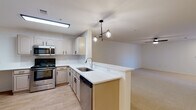 This single-floor residence offers a clean, functional layout designed for comfortable everyday living. The open-concept kitchen seamlessly connects to the living area, creating a bright and cohesive space. The kitchen is equipped with stainless steel appliances — including an electric range, over-the-range microwave, dishwasher, and refrigerator — paired with taupe cabinetry, white countertops, a peninsula with a single-basin sink, and a stylish multi-bulb pendant light fixture. Light wood-style flooring runs through the kitchen and entry areas, while a patterned tile backsplash adds a decorative touch.

The living area is generously sized with neutral carpet, white walls, a ceiling fan with light, and a front entry door flanked by a window with blinds that allows natural light to filter in.

Two bedrooms feature plush carpet, ceiling fans, natural light from windows with blinds, and sliding closets with built-in rods for ample storage. The two full bathrooms are finished consistently with warm wood-look flooring, taupe vanity cabinets with white countertops, and tiled shower-tub combos accented by a distinctive black tile border detail, giving each bathroom a classic yet polished appearance.
