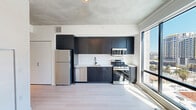 Located in the heart of downtown Phoenix, this modern 1-bedroom, 1-bathroom unit offers a thoughtfully designed open-concept layout with contemporary finishes throughout. Light wood-tone flooring flows seamlessly across the entire space, complemented by exposed concrete ceilings that lend an urban, industrial character.

The combined kitchen and living area serves as the heart of the unit. The kitchen is outfitted with sleek dark cabinetry, white countertops, a white tile backsplash, and a full suite of stainless steel appliances including a gas range, microwave, dishwasher, and refrigerator. Oversized floor-to-ceiling windows flood the living area with natural light and frame sweeping views of the Phoenix skyline.

The bedroom is a bright, minimalist retreat featuring light-filled windows with city views and a well-organized built-in closet system with shelving and hanging rods. A second closet provides additional storage convenience. In-unit laundry adds everyday practicality.

The bathroom is finished in a clean, modern style with large-format wall tiles, a glass-enclosed walk-in shower with a rainfall showerhead, a floating vanity with a backlit LED mirror, and matte black fixtures. The entrance provides a smooth transition into this efficient and stylish urban residence.