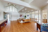 Located at 1512 Hollowhill Drive in Bryan, Texas, this single-floor community space is thoughtfully designed with a modern, open-concept layout that maximizes both functionality and visual appeal. Warm hardwood flooring runs throughout, complementing the crisp white walls and creating a welcoming, cohesive atmosphere.

The main living area is anchored by a comfortable seating arrangement featuring a cognac leather sofa, woven accent chairs, and a central coffee table, alongside a wall-mounted flat-screen TV and a low-profile media credenza. Lush indoor plants add a natural, refreshing touch to the space.

A full-height glass partition wall with sleek aluminum framing separates the lounge from an adjacent dining area, allowing natural light to flow freely between zones while maintaining a sense of definition. The dining area features light wood tables and chairs, ideal for group gatherings.

The space also includes a dedicated game room area with a foosball table and a full-length shuffleboard table set against a gallery wall of framed artwork. Soaring vaulted ceilings amplify the sense of openness throughout this zone. A connected kitchenette area with white cabinetry provides convenient service support.

Large glass doors and windows invite abundant natural light and offer direct access to an outdoor patio, seamlessly blending indoor and outdoor living.